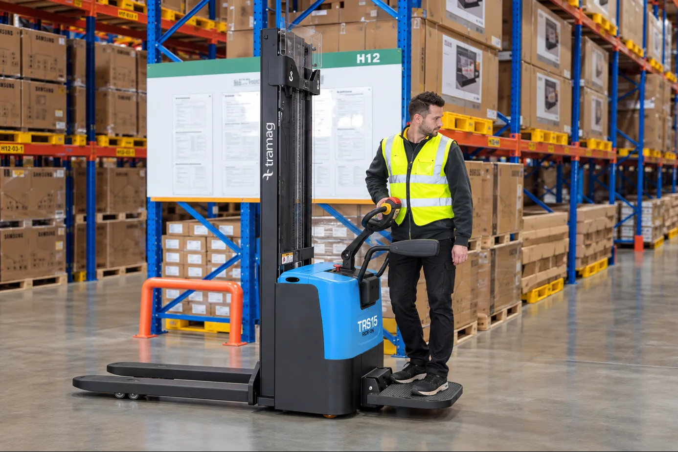 Medewerker op het meerijplatform van een Tramag TRS15 elektrische stapelaar in een magazijn.